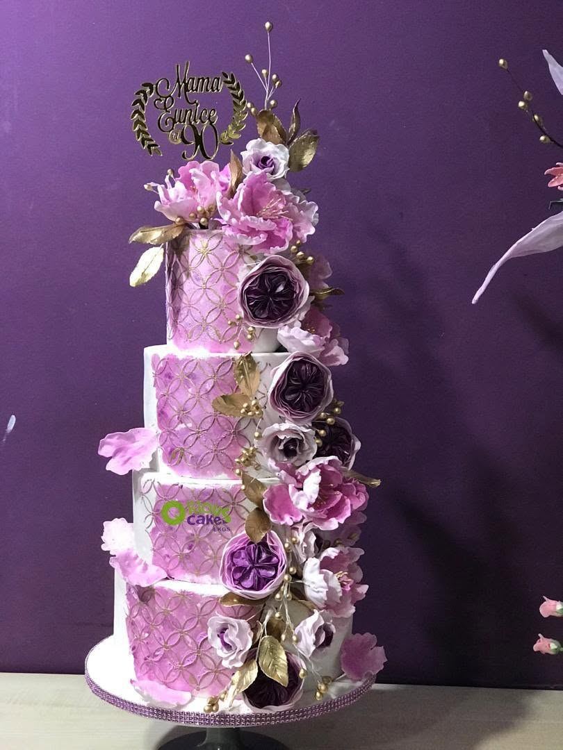 Four-tier cake with pink and purple sugar peonies and gold leaves