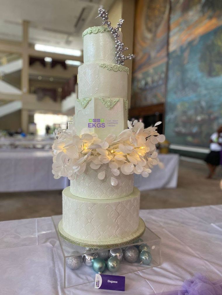 Tall ivory cake with lit wafer paper leaves and silver berries