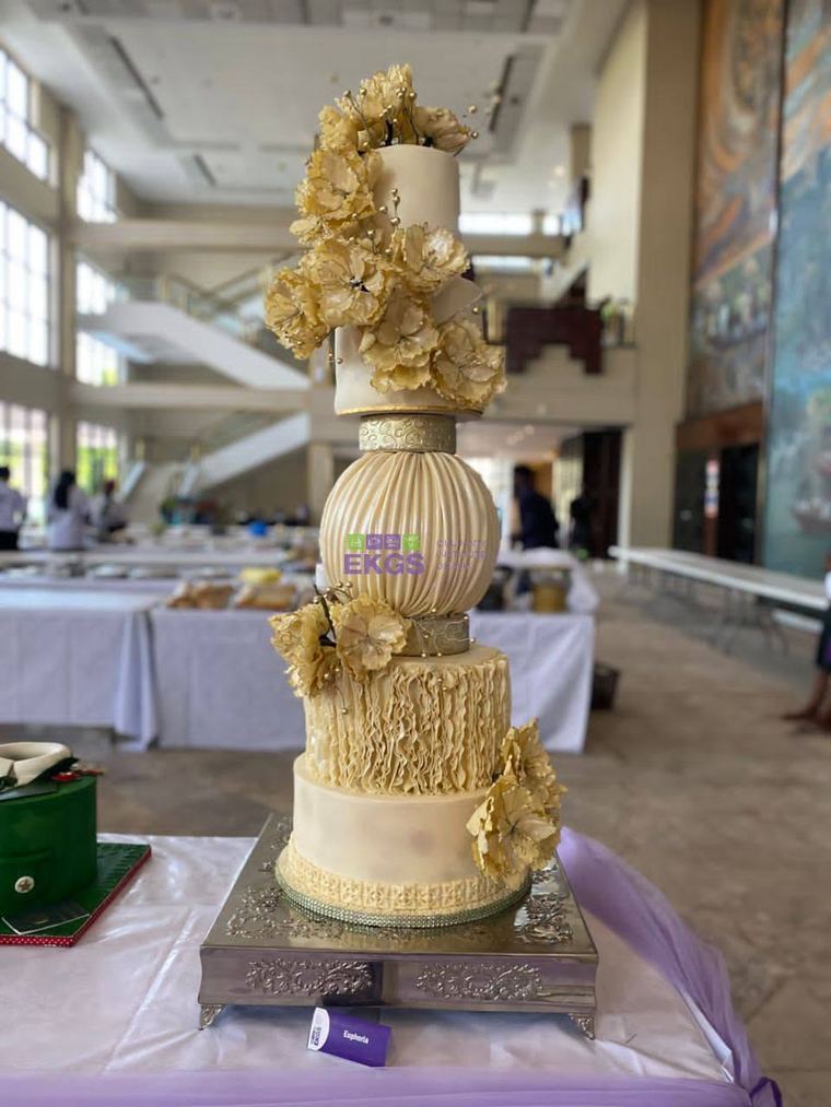 Ivory and gold tiered cake with ruffles, a pleated sphere and gold sugar flowers