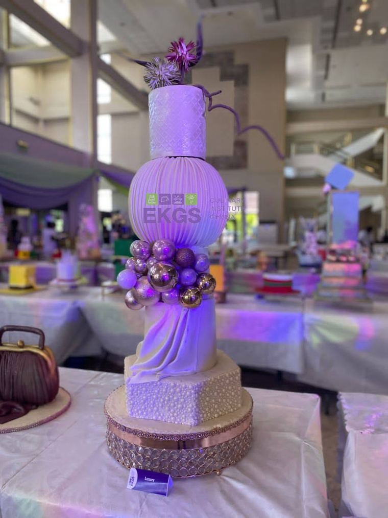 Tall cake with a pleated sphere, metallic baubles and draped fondant