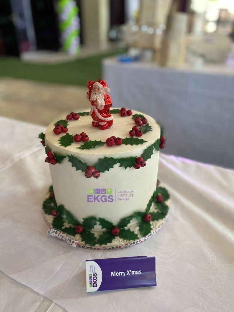 White Christmas cake with holly leaves, berries and a Santa topper