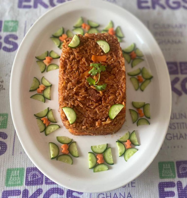 Plated jollof rice with cucumber garnish, made at EKGS